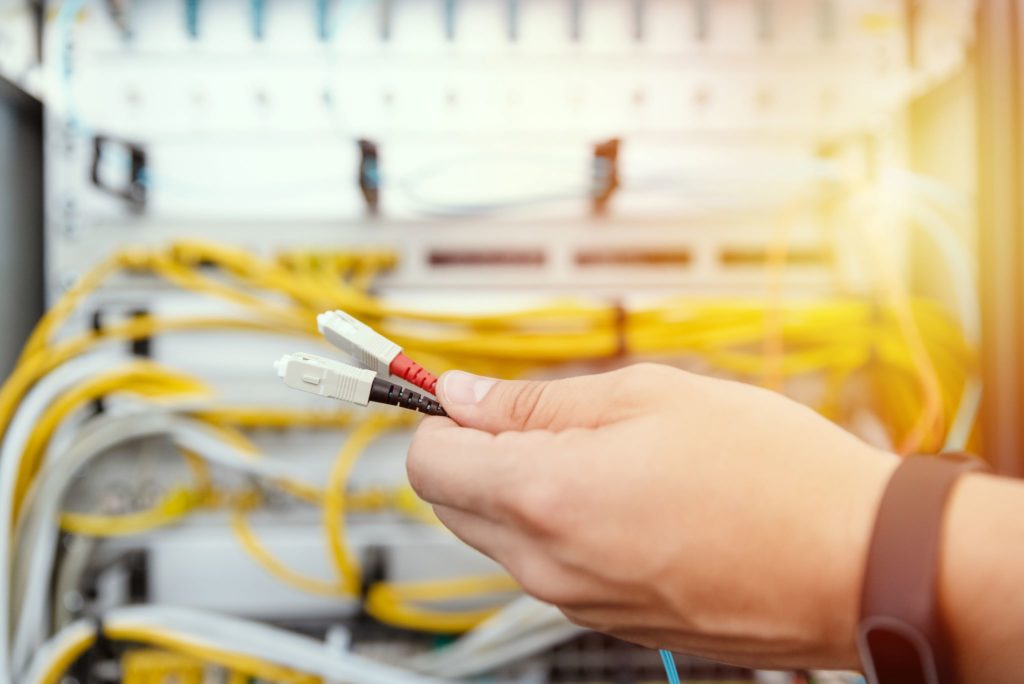 IT specialist connecting new fiber optic design cables to network equipment