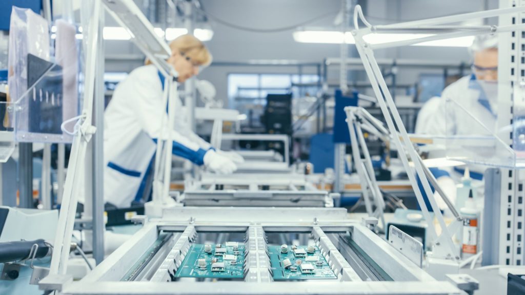 Electronics factory workers assembling circuit boards in a high tech assembly facility.