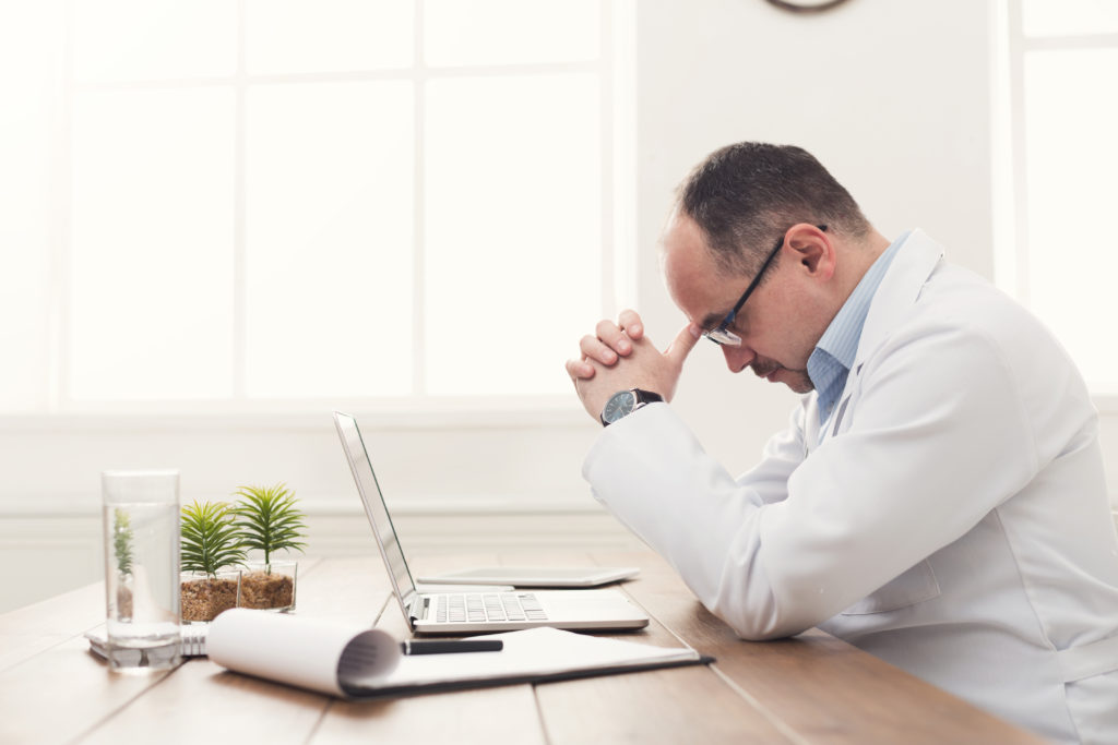 Tired technician sitting at does wondering how supply chain risk management best practices could help his situation