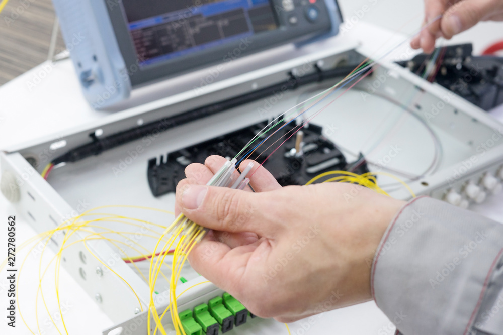Technicians hands splicing fiber optic cable on a splicing tray